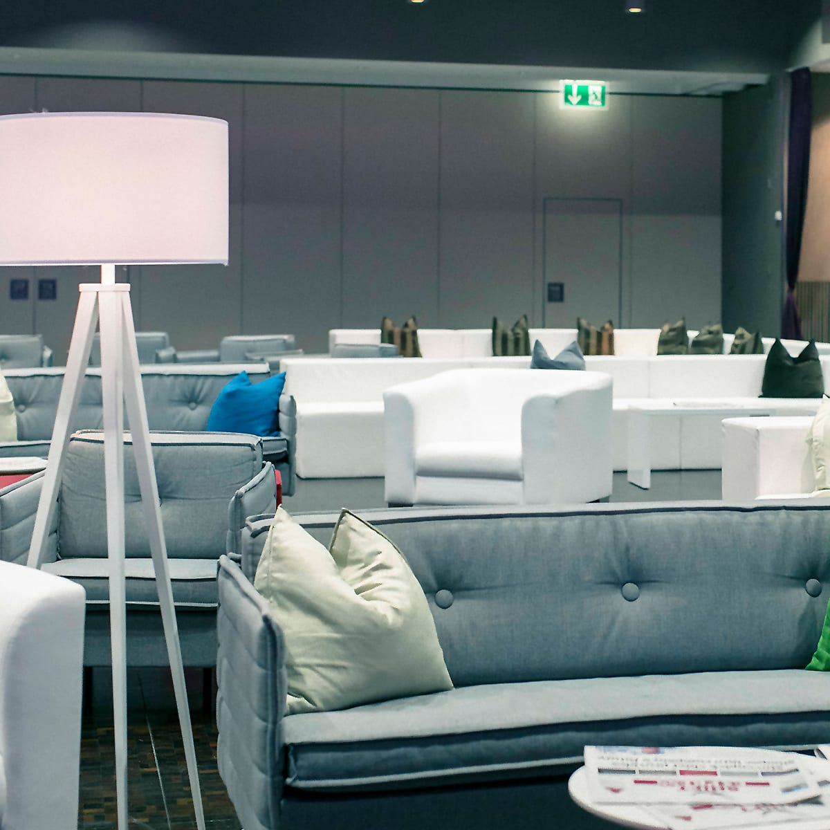 weisse Stehlampe mit weissem Lampenschrim an Seminar mit diversen Sitzelementen